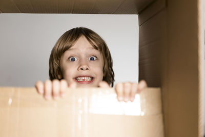 Cute toddler boy playing in cardboard box at new home.
