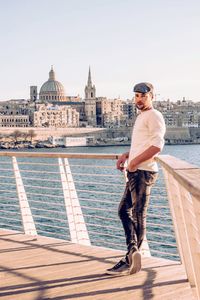 Portrait of man standing by sea against historic church