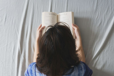 Woman reading book on bed at home