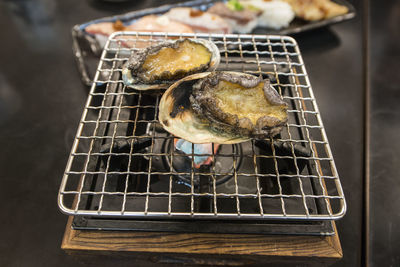 High angle view of oysters on metal grate at stove