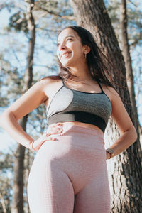 Portrait of young woman standing against trees