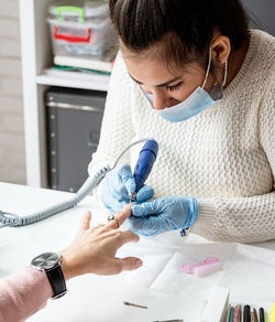 Young woman wearing glove and mask working at salon