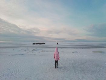 Rear view of woman walking on snow against sky