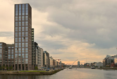 Modern buildings in city against sky during sunset