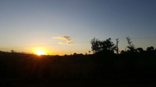 Silhouette trees on landscape against clear sky during sunset