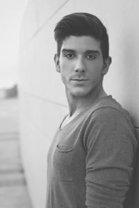 Portrait of confident young man standing by wall