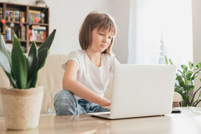 Schoolgirl girl studies at home through a laptop, makes a video call or communicates with friends 