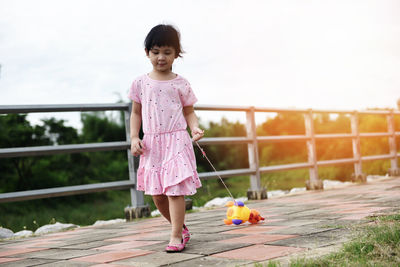 Full length of girl with toy walking on footbridge