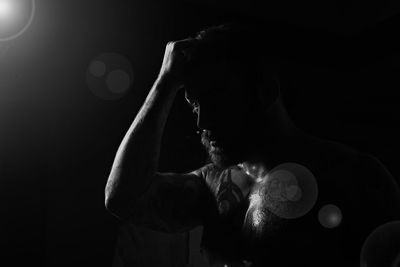 Close-up of man with hand in hair at darkroom