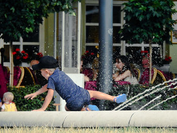 Full length of boy sitting by fountain outdoors