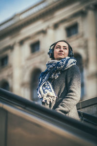 Woman listening music while standing in city