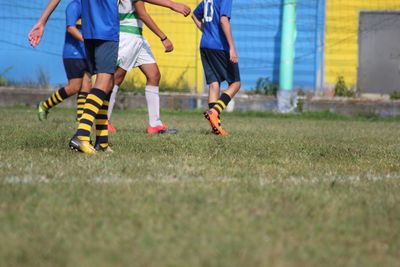 Low section of people playing soccer on field