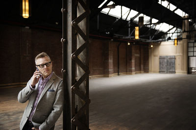 Businessman talking on smart phone while standing in empty warehouse