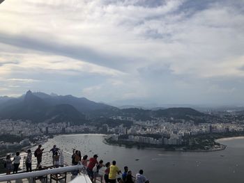 People on city by mountain against sky