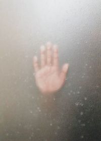 Close-up of hand on wet glass window