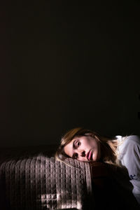 Portrait of young woman standing against black background