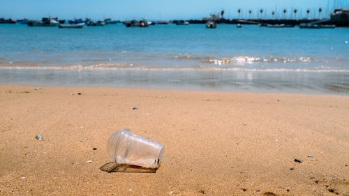 Rubbish plastic cup left on the beach make pollution.