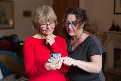 Smiling young woman using smart phone at home