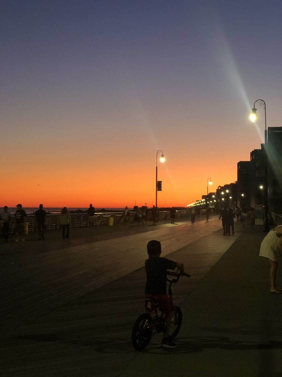 PEOPLE RIDING BICYCLE ON ROAD AT SUNSET