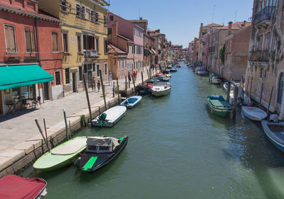 Boats moored in canal amidst buildings in city