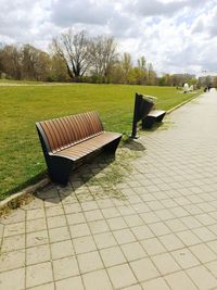A wooden bench in front of a large lawn