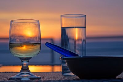 Close-up of wine glass on table against sky during sunset