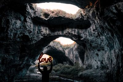 Rear view of woman holding love text in cave
