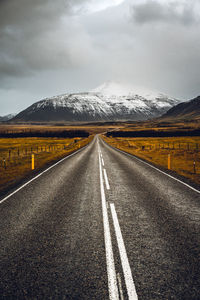 Road leading towards mountains against sky