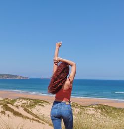Rear view of woman at beach against clear blue sky