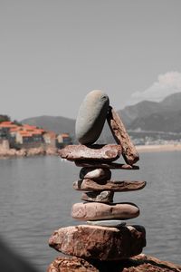Stack of stones by sea against clear sky