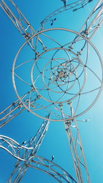 Low angle view of birds on cables against blue sky