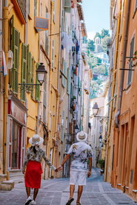 Rear view of people walking on street amidst buildings in city