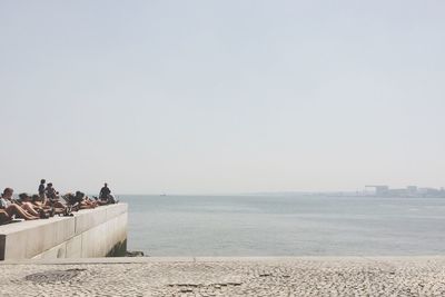 People at beach against clear sky