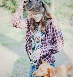 Woman with dog standing on field