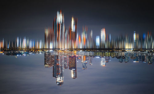 Illuminated commercial dock by river against sky at night