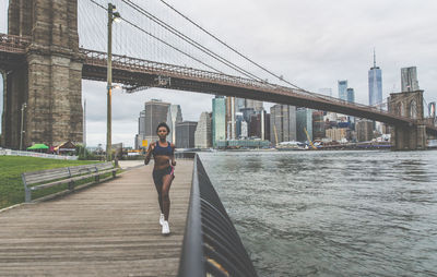 Full length of woman running on promenade in city