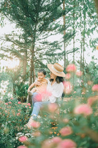 People standing by flowering plants against trees