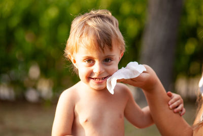 Portrait of shirtless boy holding baby outdoors