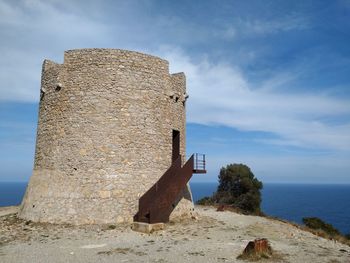 Old ruin building by sea against sky