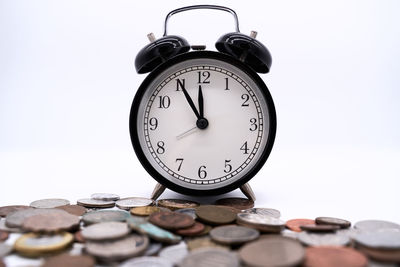 Close-up of alarm clock and coins on white background