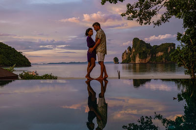 Reflection of man standing on lake against sky