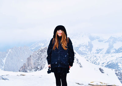 Woman standing on snow covered mountain against sky