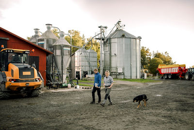 Mature farmers with dog walking at dairy factory