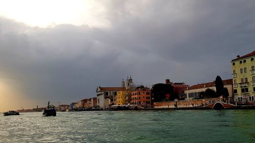 View of buildings at waterfront against cloudy sky