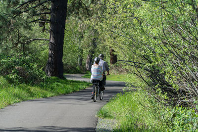 Rear view of couple riding bicycle on road