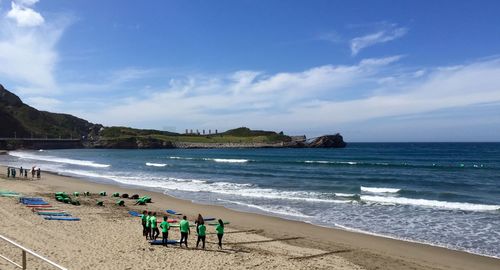 Surfing instructor giving lesson to group on beach