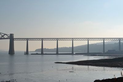 Bridge over river against sky in city