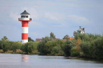 Lighthouse by sea against sky