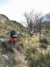 Rear view of woman walking on trail against sky