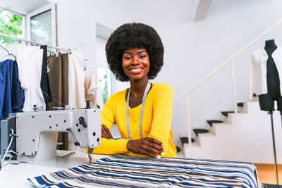 Portrait of smiling fashion designer sitting at boutique